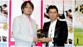 トロフィーを手に笑顔の本木さんと脚本の小山薫堂さん。