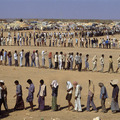 Refugees in the desert. The Sha-alaan One camp, is the worst camp. They have orderly food lines with thousands of refugees waiting calmly for food distribution from the “Charitas” charity organization. Jordan, 1990.
