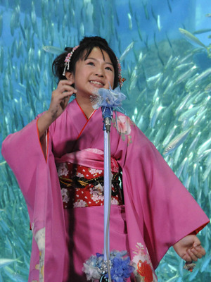 イワシをバックに熱唱